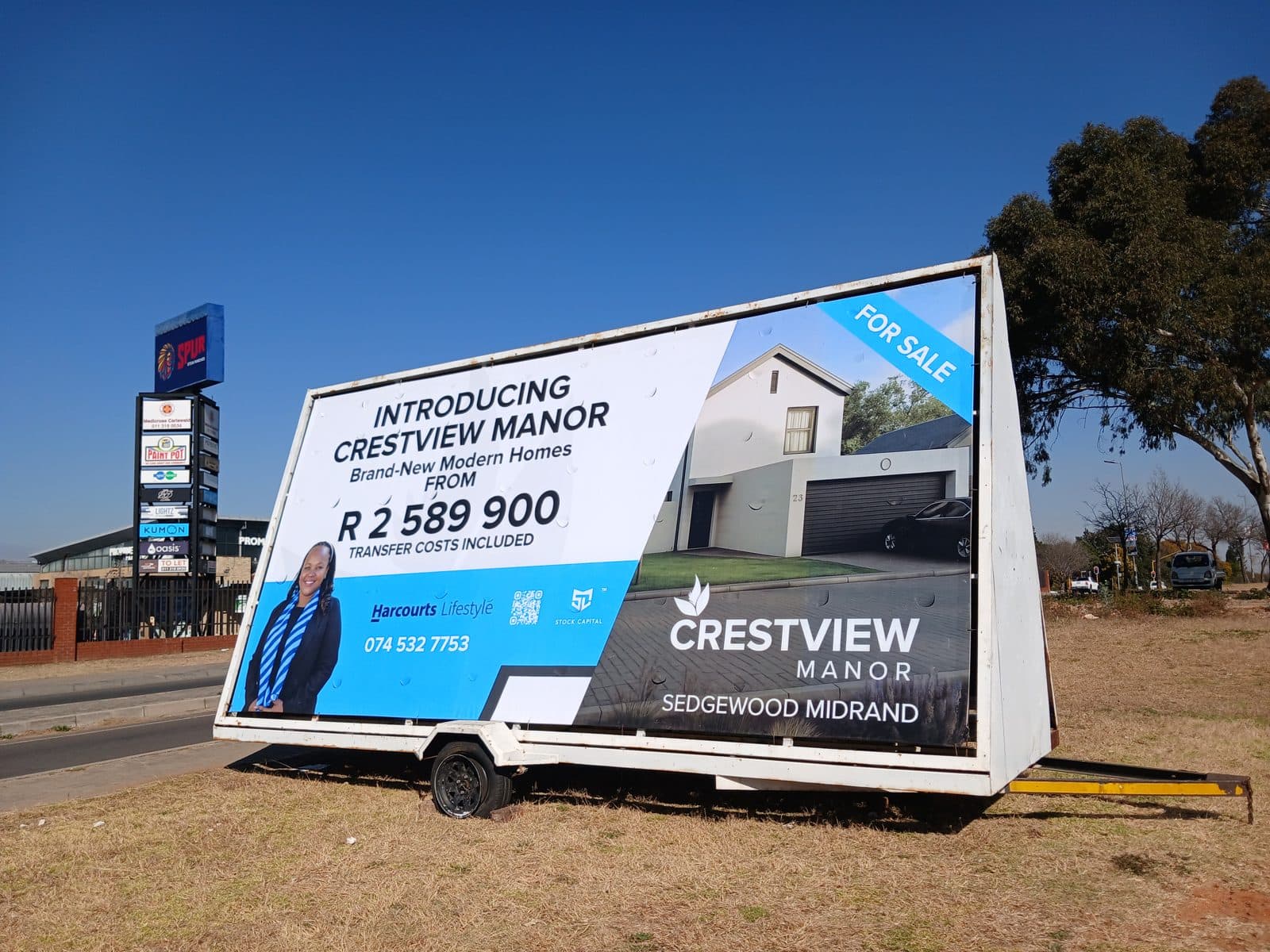 RE/MAX Masters agent billboard on a Simply Visible trailer at a traffic-light intersection